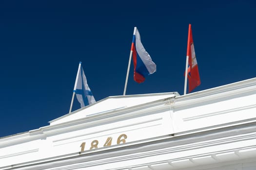 Sevasopol, Crimea. Flags on top of a white colonnade against a blue sky.
