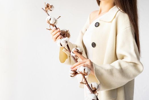 Beauty and youth Concept. Beautiful woman in cozy clothes holding branch of cotton flowers