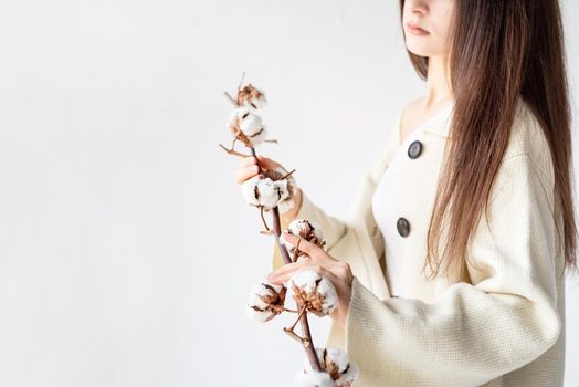 Beauty and youth Concept. Beautiful woman in cozy clothes holding branch of cotton flowers