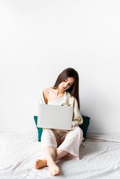 Beautiful young woman sitting on the floor and doing freelance project on laptop, using computer
