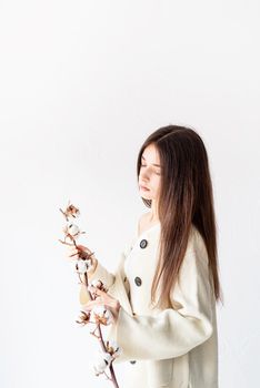 Beauty and youth Concept. Beautiful woman in cozy clothes holding branch of cotton flowers