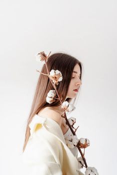 Beauty and youth Concept. Beautiful woman in cozy clothes holding branch of cotton flowers