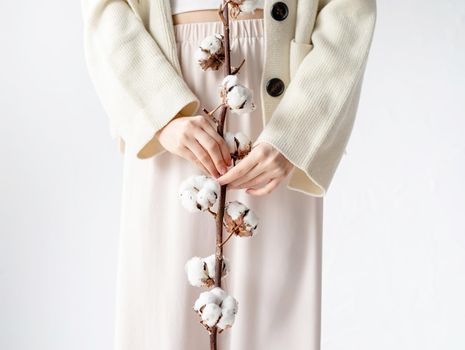 Beauty and youth Concept. Beautiful woman in cozy clothes holding branch of cotton flowers