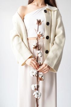 Beauty and youth Concept. Beautiful woman in cozy clothes holding branch of cotton flowers