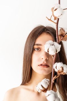 Beauty and youth Concept. Beautiful woman in cozy clothes holding branch of cotton flowers