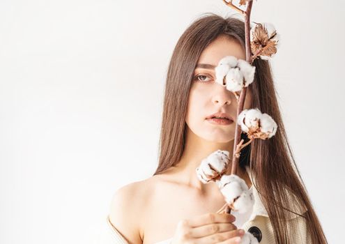 Beauty and youth Concept. Beautiful woman in cozy clothes holding branch of cotton flowers