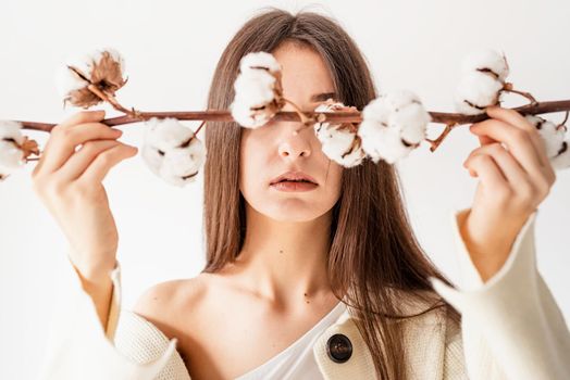 Beauty and youth Concept. Beautiful woman in cozy clothes holding branch of cotton flowers