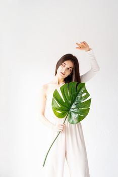 Spa and beauty. Self care and skin care. Happy beautiful woman in cozy clothes holding a green monstera leaf