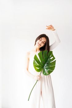 Spa and beauty. Self care and skin care. Happy beautiful woman in cozy clothes holding a green monstera leaf
