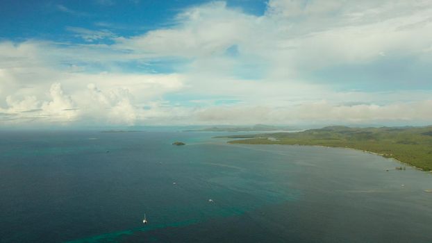 Tropical island with palm trees and beach against the sky and clouds, aerial view. Philippines, Siargao. Summer and travel vacation concept