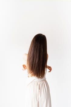 Light and airy. beautiful young woman with long hair in white cozy clothes on white background, view from behind