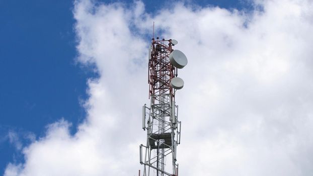 Cell phone tower against a blue sky. Tower of communications with a lot of different antennas under blue sky and clouds. Telecommunication tower with blue sky.