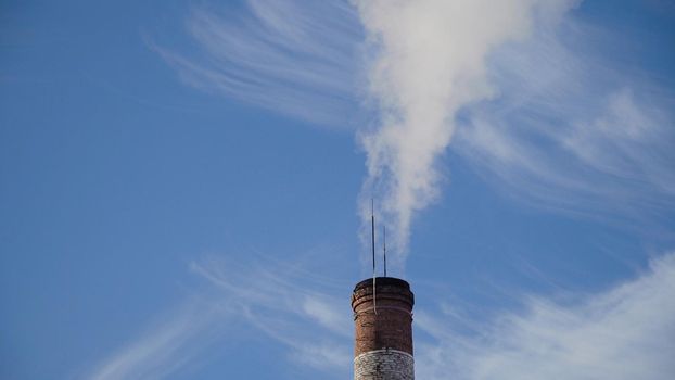 Boiler room in the winter season, from the chimneys rise up clouds of steam. Pipes of a thermal power plant. Boiler house, pipe plant, boiler plant.