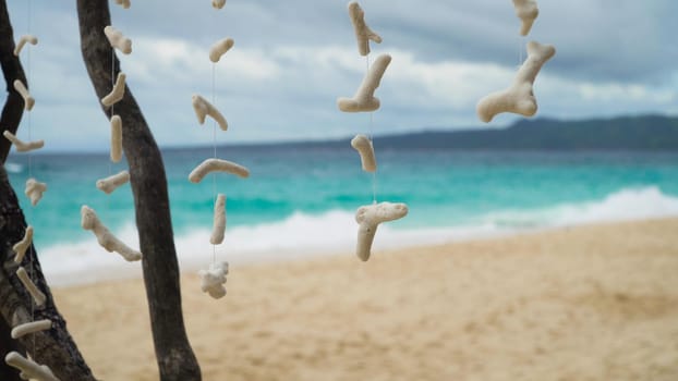 White corals, sea shells on suspension with the sand beach sea ocean background. Corals on the rope. Vintage effect. Shallow focus. Holiday travel concept.