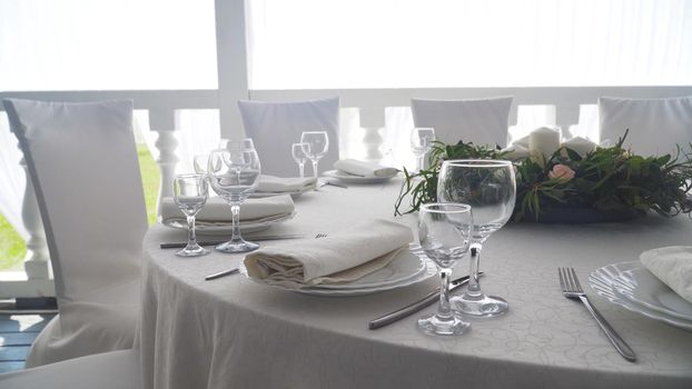 Banquet decorated table, with cutlery. Wedding decor in the banquet hall.Serving of a festive table, plate, napkin, knife, fork. Table setting decoration. Romantic Dinner or other events.
