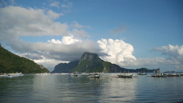 Mountain island, rocks, sea, clouds. Sailing boats and yachts in the bay, tropical lagoon. Seascape with island, mountains, boats on the water. Tropical landscape. Tropical island. Philippines, El Nido. Travel concept
