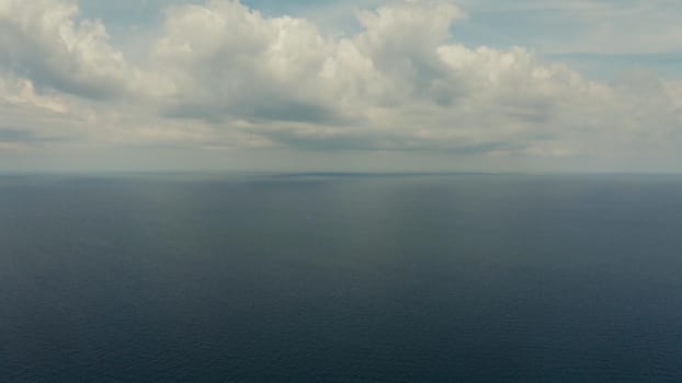 Sea surface with waves against the blue sky with clouds, aerial view. Water cloud horizon background. Blue sea water with small waves against sky.