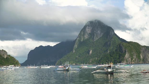 Mountain island, rocks, sea, clouds. Sailing boats and yachts in the bay, tropical lagoon. Seascape with island, mountains, boats on the water. Tropical landscape. Tropical island. Philippines, El Nido. Travel concept