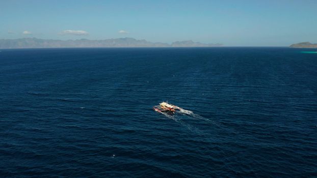 Aerial view tour boat in sea. Seascape blue sea and tropical islands. traditional Filipino wooden outrigger boat called a banca . Motorboat crossing ocean. Banca boat in the Philippines Palawan