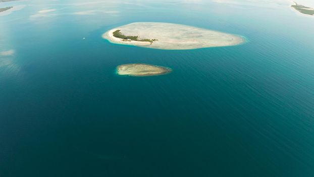 Tropical island and sandy beach with tourists surrounded by coral reef and blue sea in honda bay, aerial view. Island with sand bar and coral reef. starfish island. Summer and travel vacation concept, Philippines, Palawan