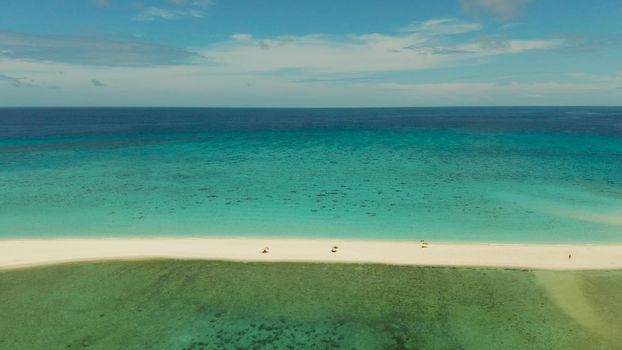 Tropical white island and sandy beach with tourists surrounded by coral reef and blue sea, aerial view. Sandbar Atoll. Island with sand bar and coral reef. Summer and travel vacation concept, Camiguin, Philippines.