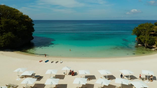 Tropical sandy beach with sun beds near the lagoon with turquoise water from above, Boracay, Philippines, aerial view. Seascape with beach on tropical island. Summer and travel vacation concept.