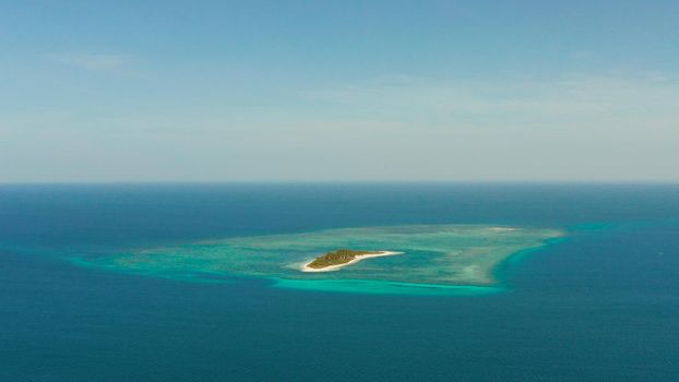 Small tropical island in the blue sea with a coral reef and the beach, top view. Summer and travel vacation concept. Canimeran Island, Balabac, Palawan, Philippines.