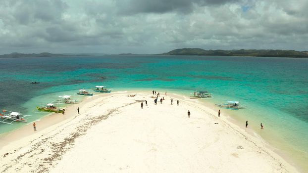 Beautiful beach on tropical island surrounded by coral reef, sandy bar with tourists, top view. Sandbar Atoll. Summer and travel vacation concept, Naked Island, Siargao.