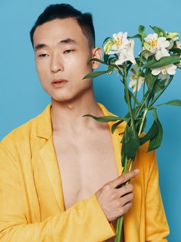 man of asian appearance with bouquet of white flowers and holidays gifts blue background. High quality photo