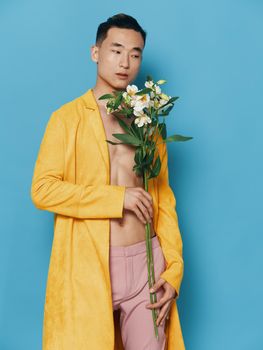 male korean appearance with a bouquet of flowers in a yellow coat and pink trousers. High quality photo