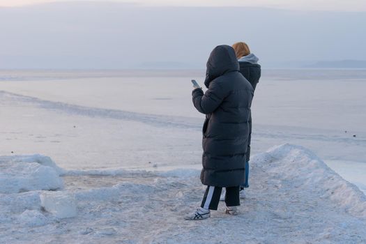Vladivostok, Primorsky Krai. People in winter clothes standing on the icy surface of the sea.