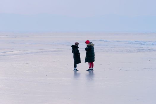 Vladivostok, Primorsky Krai. People in winter clothes standing on the icy surface of the sea.
