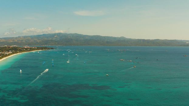 Tropical lagoon with turquoise water, sailing yachts and white sand beach from above. Boracay, Philippines. White beach with tourists and hotels. Summer and travel vacation concept.