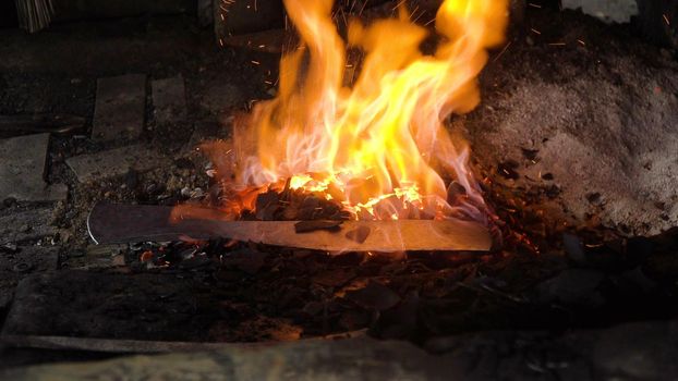 Blacksmith furnace with a hot iron, burning embers, sparks. Blazing furnace with burning coal at the blacksmith's. Blacksmiths make machete. Philippines.