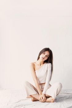 Light and airy. Portrait of beautiful woman in white cozy clothes sitting on the floor