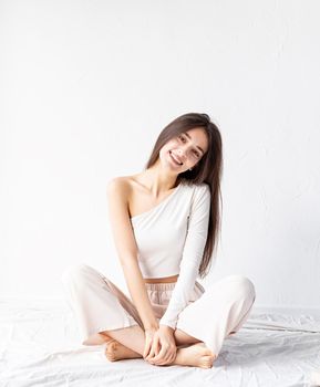 Light and airy. Portrait of beautiful woman in white cozy clothes sitting on the floor