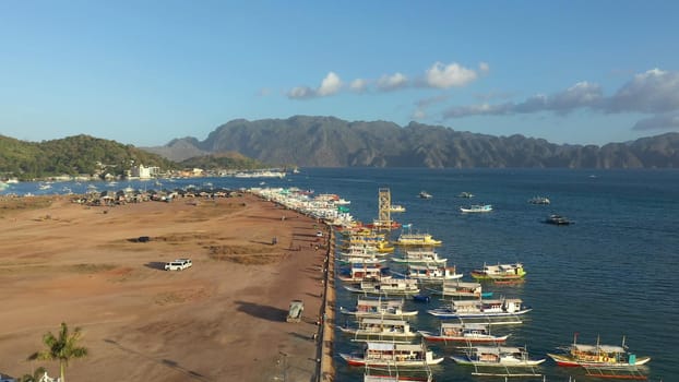 aerial view Pier and promenade Coron town with boats on Busuanga island. Wooden boats waiting at pier. Seascape with mountains. Philippines, Palawan