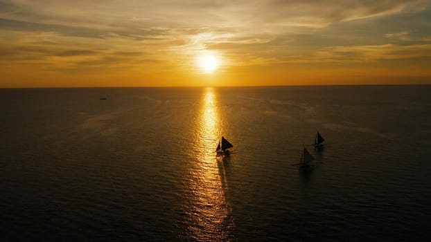 Sunset above the sea surface with sail boats, aerial view Boracay, Philippines. Reflected sun on a water surface. Sunset over ocean. Seascape, Summer and travel vacation concept