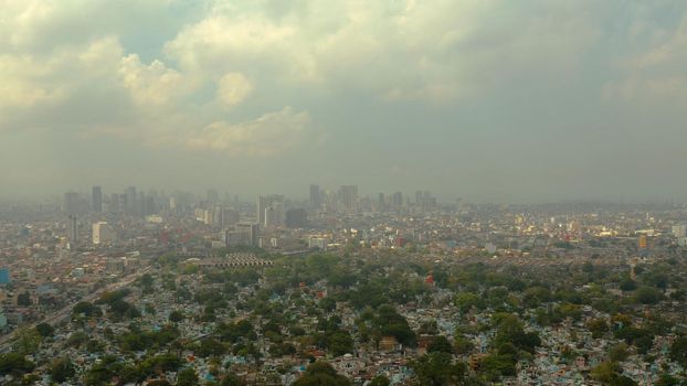 Manila North Cemetery on the background of skyscrapers and modern buildings, aerial drone. Travel vacation concept