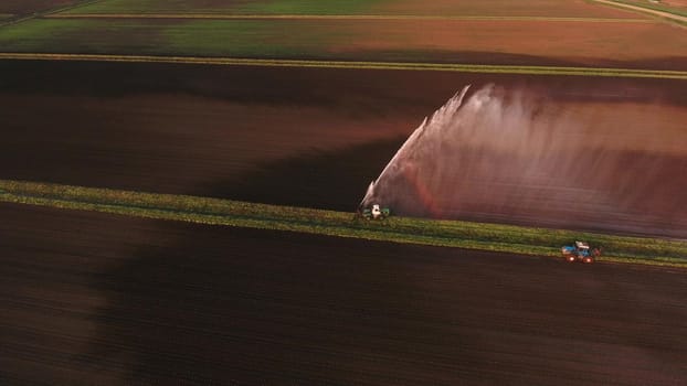 Irrigation equipment watering freshly seeded field.Irrigation at sunset.Irrigation of farmland to ensure the quality of the crop. Aerial view:irrigation system watering a farm field.
