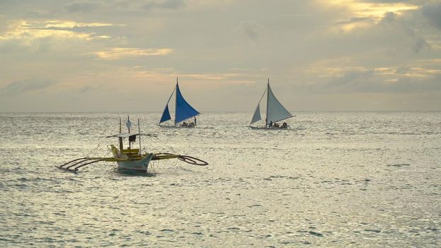 Sailing ship yachts with blue sails in the ocean at the sunset. Sailing boat on sea. Sailing ship yachts in the sea. Philippines, Boracay. Travel concept.