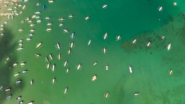 Many boats in the turquoise lagoon near city El nido, aerial view. Seascape with blue bay and boats view from above. Palawan, Philippines. traditional Filipino wooden outrigger boat called a banca. Summer and travel vacation concept