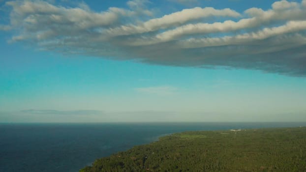 Beautiful skyscape with white clouds over the coast of the island and the blue sea, aerial view. Seascape: Ocean and sky.Philippines, Camiguin.
