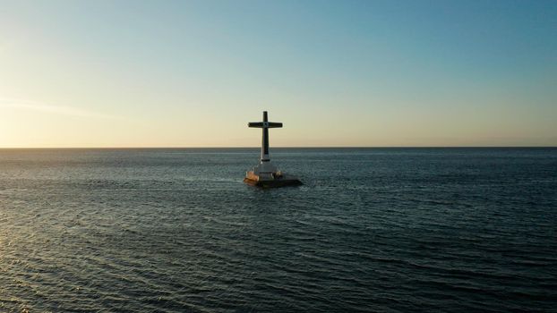 Catholic cross in sunken cemetery in the sea at sunset, aerial view. Sunset at Sunken Cemetery Camiguin Island Philippines.