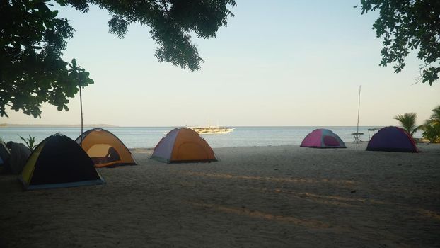 Camp on a tropical beach with tents in the early morning. Camp with tourists on a tropical island. Summer and travel vacation concept