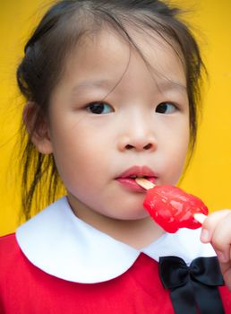 Little girls in red student dressed Eating a red popsicle