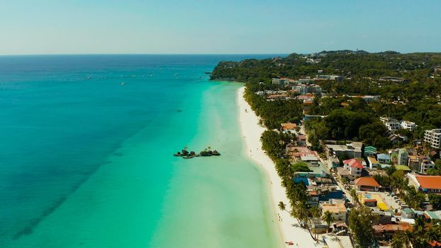 Tropical white beach with tourists and hotels near the blue sea, aerial view. Summer and travel vacation concept.