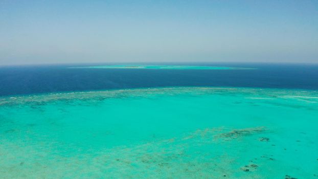 Tropical coral atoll with turquoise water against the sky with clouds top view. Summer and travel vacation concept. Balabac, Palawan, Philippines