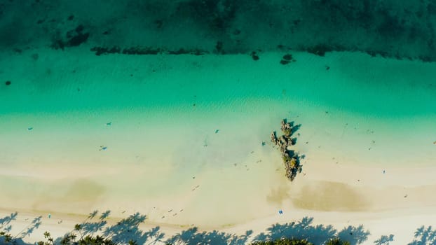 White sandy beach with tourists and azure water of the lagoon,copy space for text, top view. Ocean with waves and tropical beach. Summer and travel vacation concept