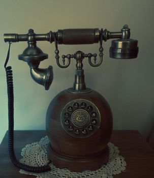 Antique fixed telephone with earphone and made of wood